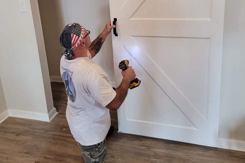 Crew member installing a white sliding barn door