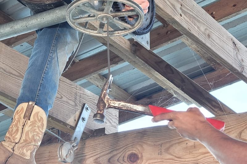 Crew member working on a boat lift motor under a boathouse roof