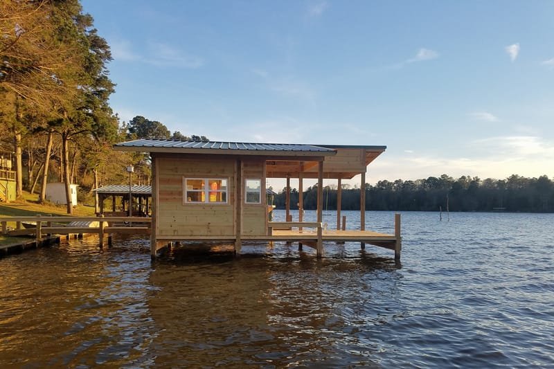 Boathouse with an enclosed room and a covered deck, seen from the water