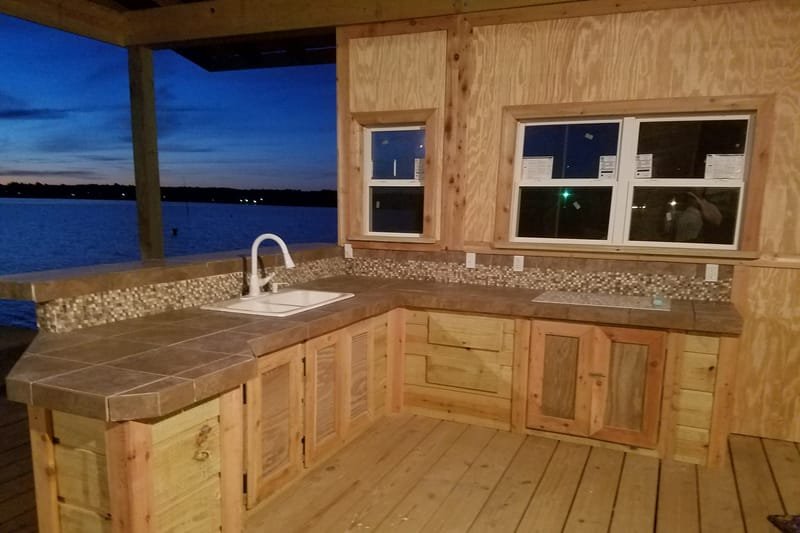 Boathouse kitchen with tile counters, a sink and windows over the lake