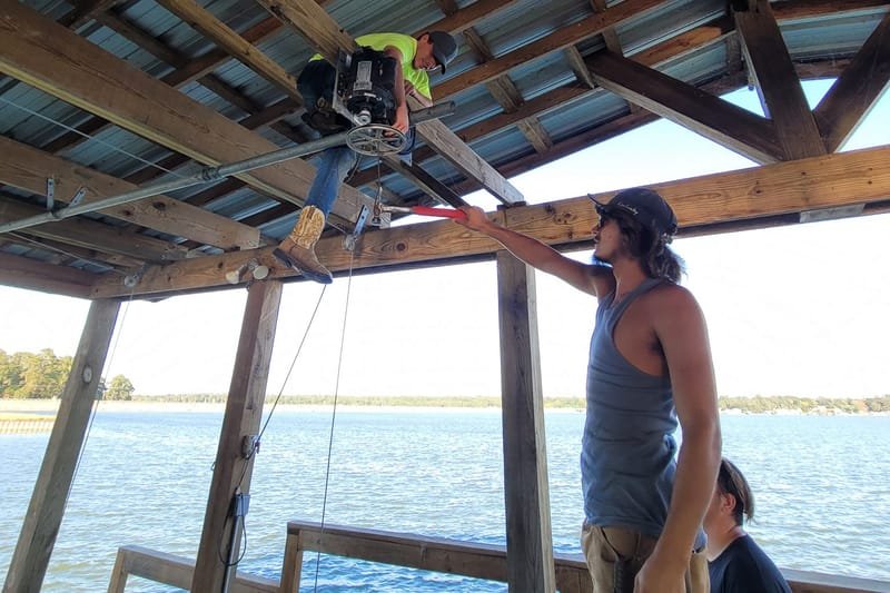 Crew working on a boat lift inside a boathouse on the lake