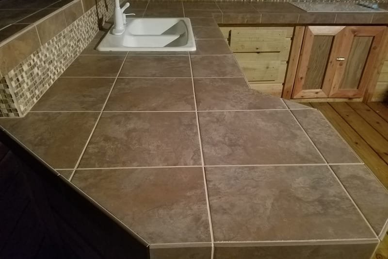 Tile countertop with a sink and stone backsplash inside a boathouse