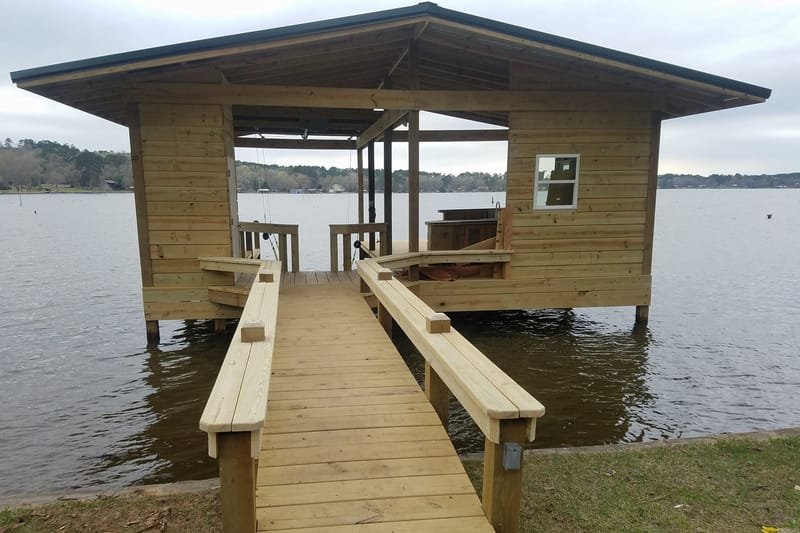 Pier walkway with benches on both sides leading to a covered boathouse