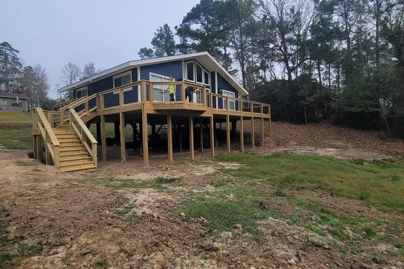 Raised house on piers with a new deck and stairs above freshly graded ground