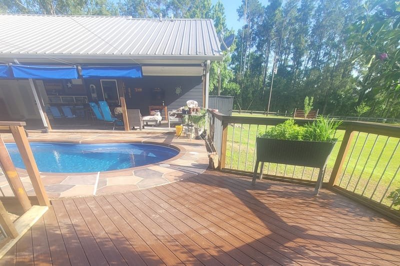 Stained wood deck with metal railings next to an in-ground pool
