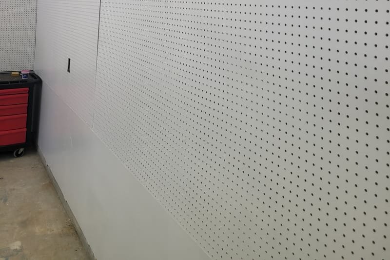 Garage wall finished with drywall and a pegboard panel