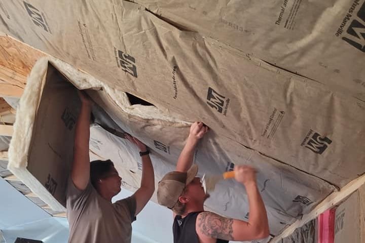 Crew installing insulation in a ceiling