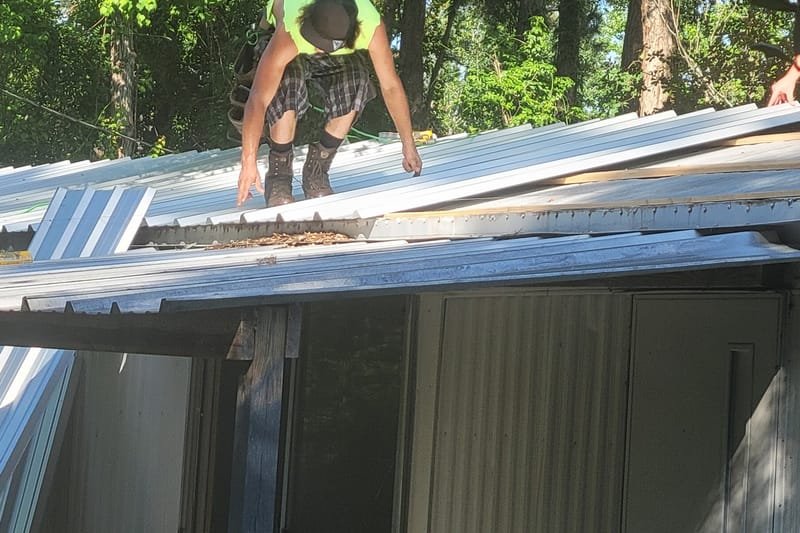 Crew member installing metal roofing panels on a mobile home