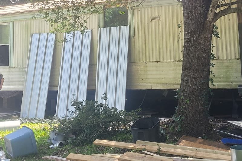 Metal roofing panels staged beside a mobile home