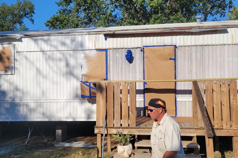 Mobile home with windows covered, prepped for paint