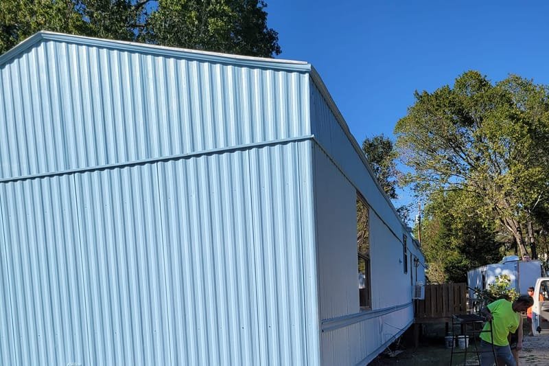 End view of a freshly painted light blue mobile home