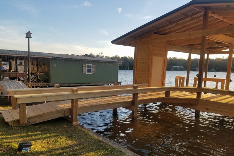L-shaped pier walkway with benches and a lamp post leading to a boathouse