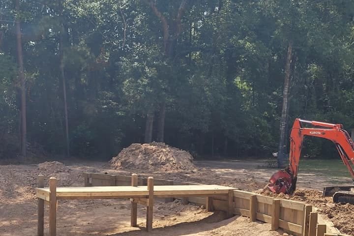 Excavator and new timber bulkhead at a private pond site