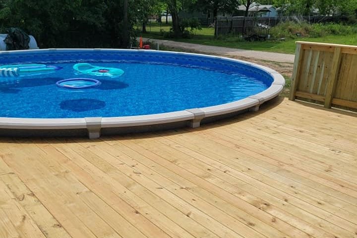 New wood deck built level with the edge of a round above-ground pool