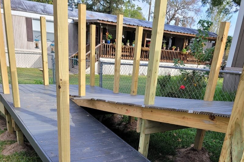 Gray composite ramp under construction beside a porch