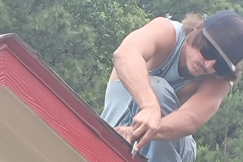Crew member working along a roof edge above red trim