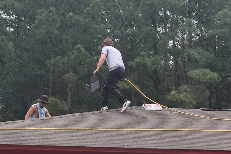 Two roofers working on a shingle roof