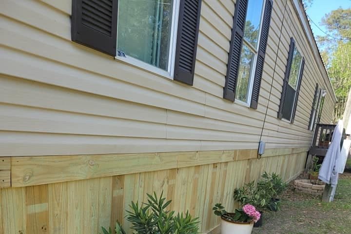 Wood skirting along a mobile home, with potted plants in front