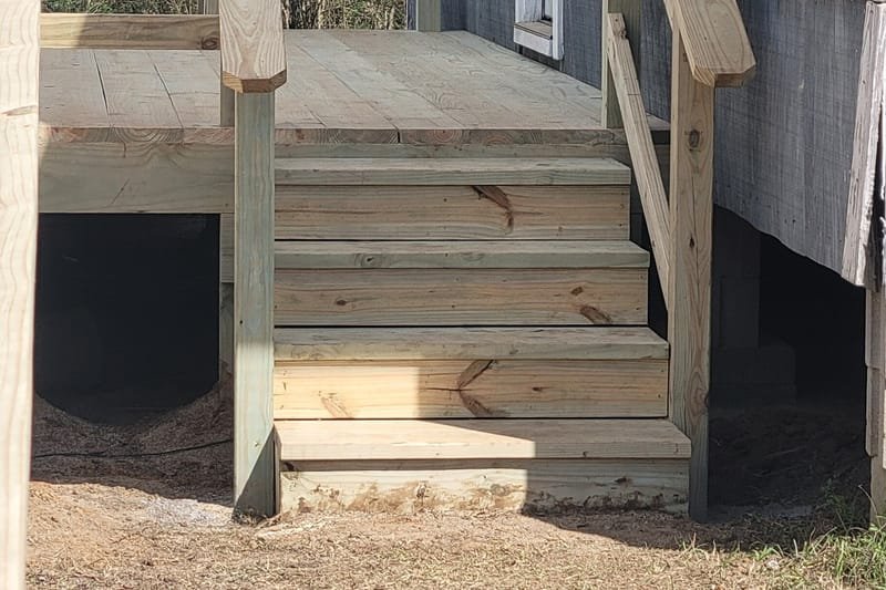Wooden steps and landing with railings at a side door