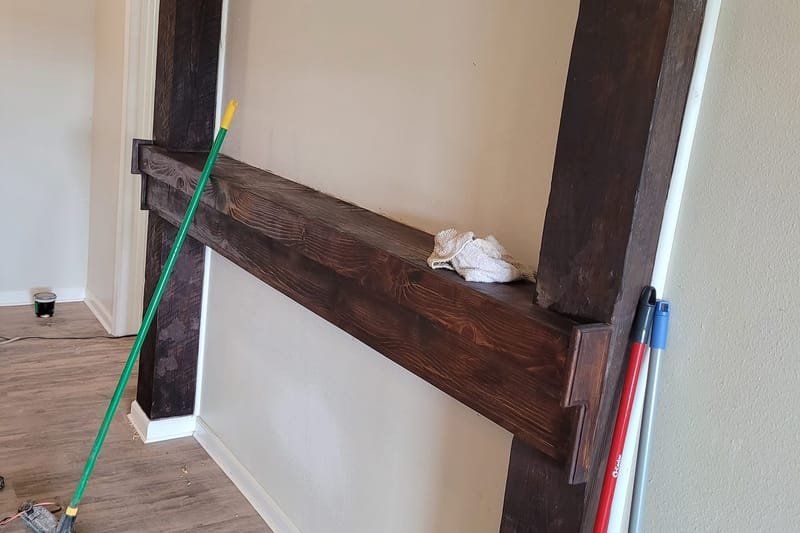 Dark wood beam mantel and posts installed on a living room wall