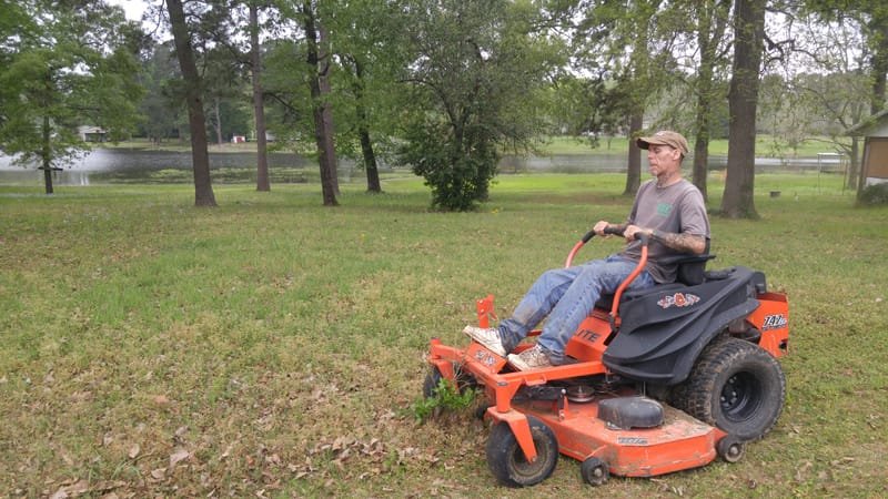 Crew member mowing a large lawn with a zero-turn mower